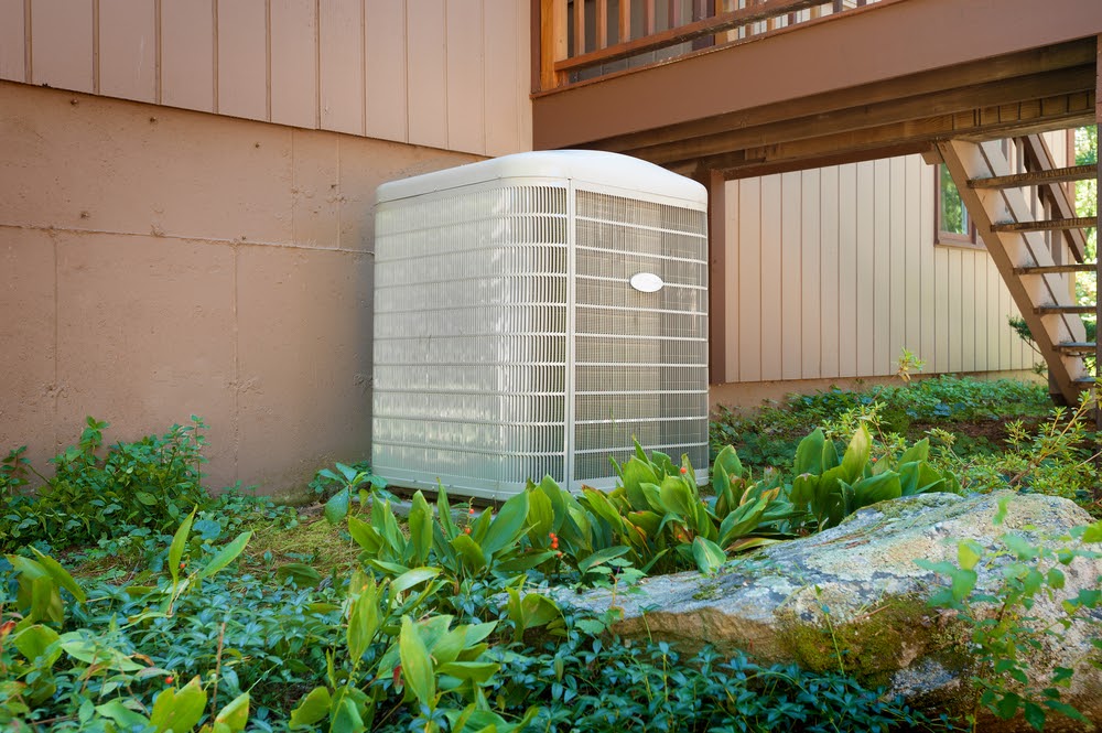 A residential central air conditioning and heating unit sitting outside a home.